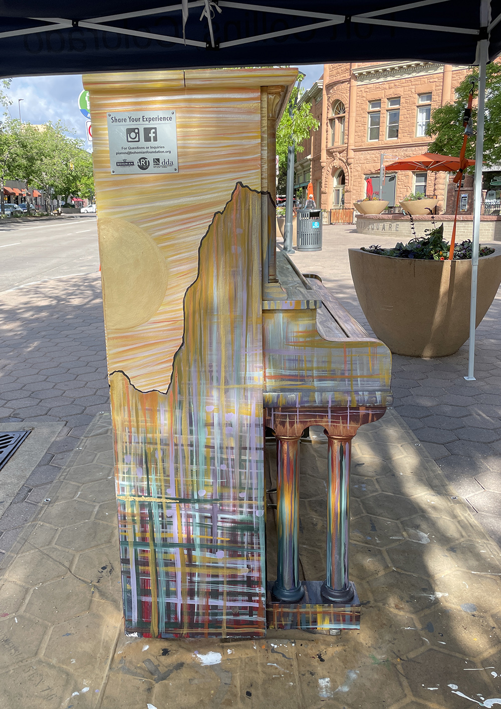 side of painted piano with stone building in the back.