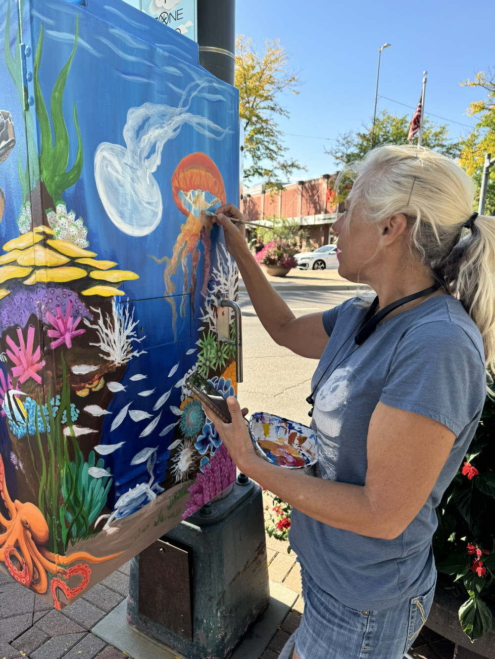 Shawna Turner painting an ocean themed mural on a traffic cabinet.