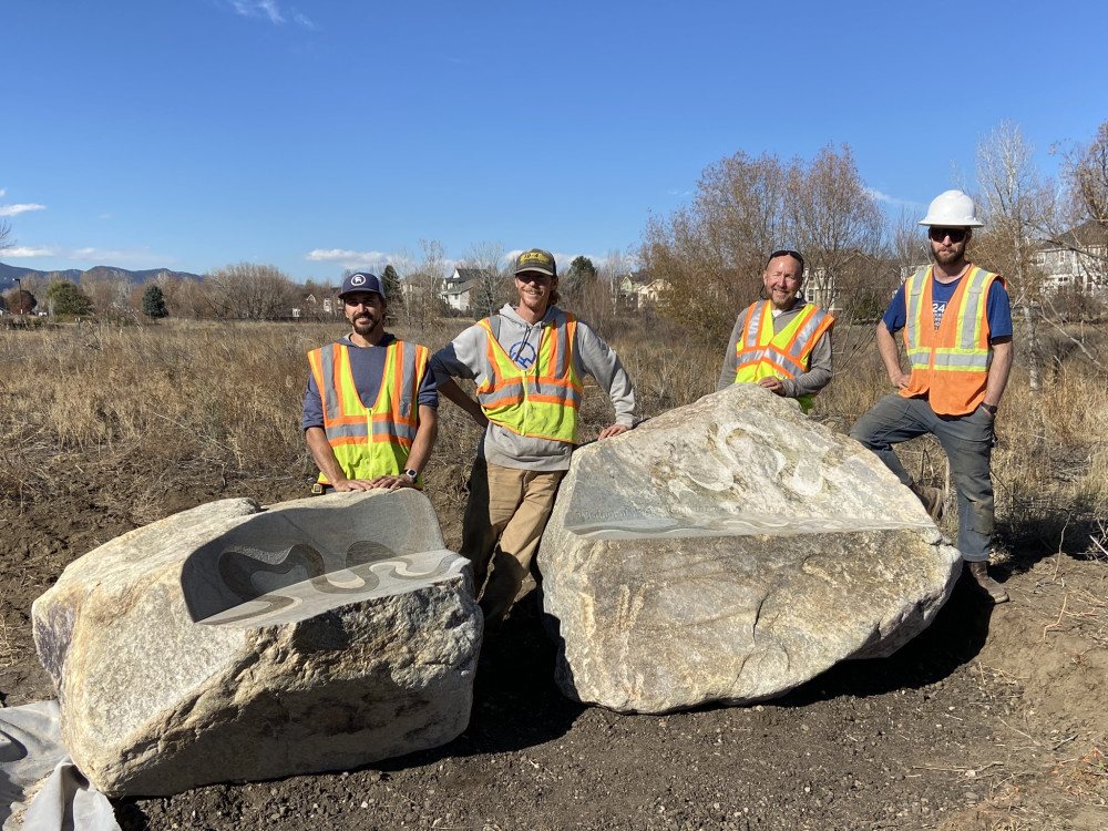 four men in reflective vests behind stone benches