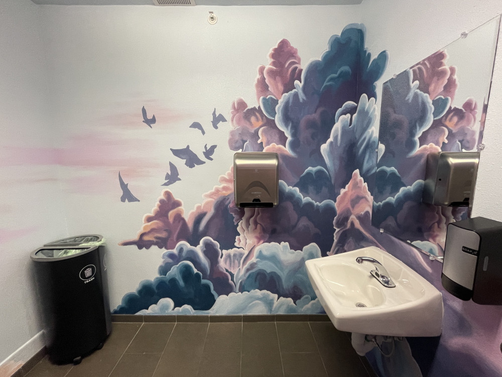 mural of pink and purple clouds with silhouettes of birds