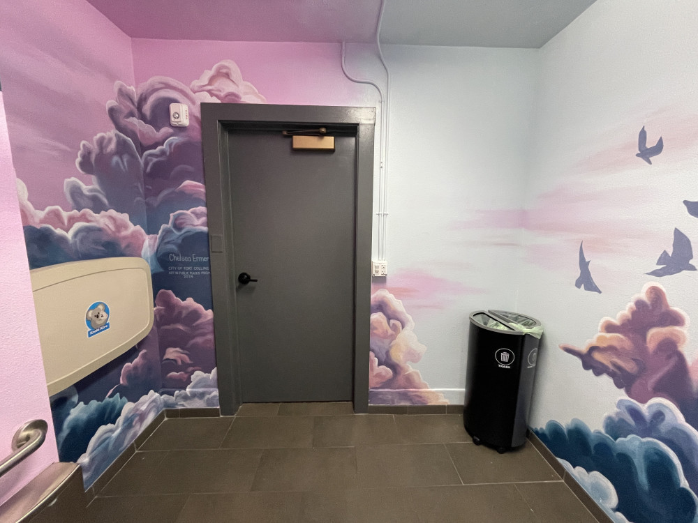 mural of pink and purple clouds with silhouettes of birds