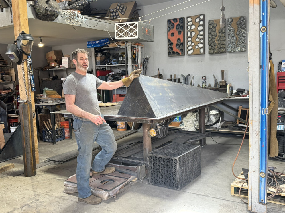 artist standing in front of triangular sculpture