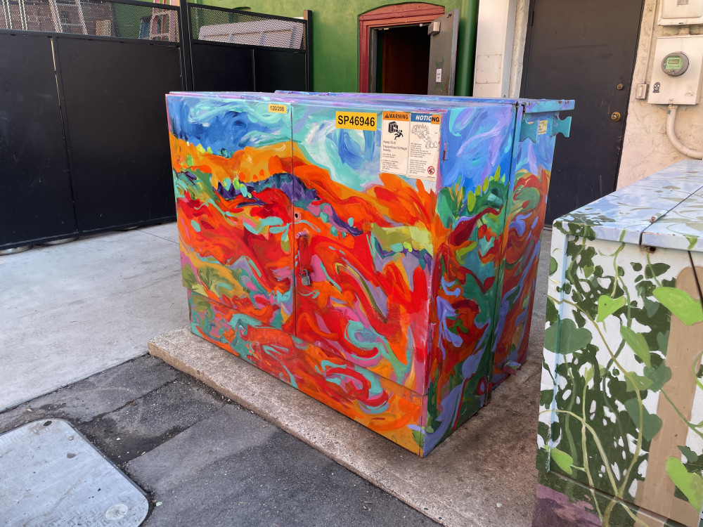 mural on a transformer cabinet with bright orange and red swirls