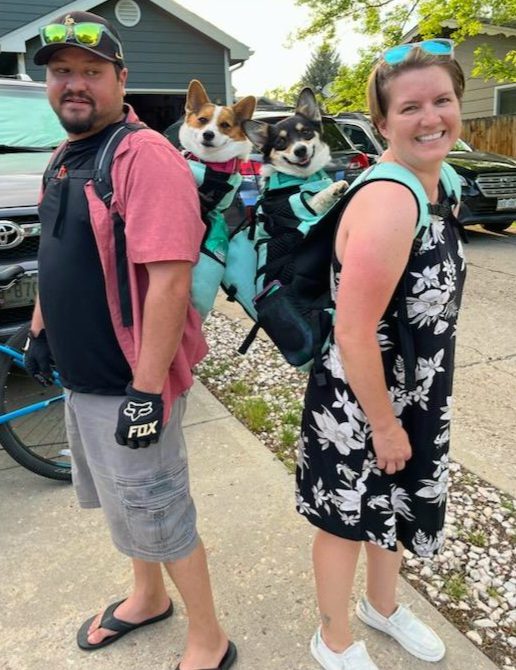 Photo of Courtney and her husband with their dogs in backpacks.