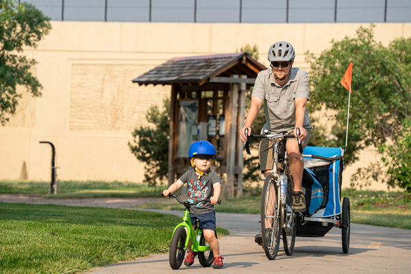 A child and adult ride bikes on a City trail