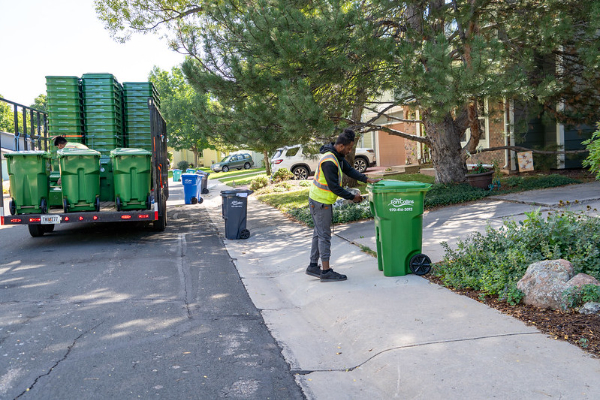 A person placing a waste cart at a resident's driveway