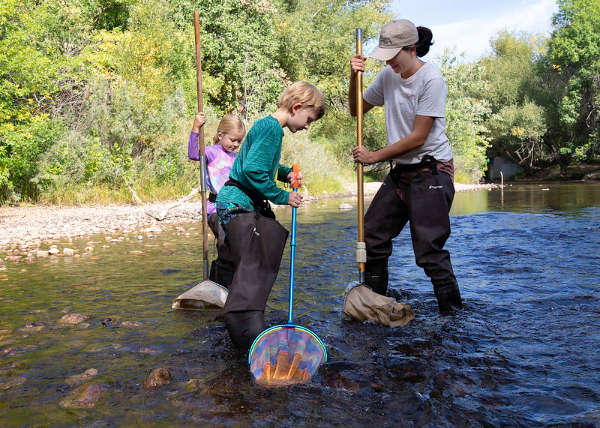 An adult and two children holding nets in a river