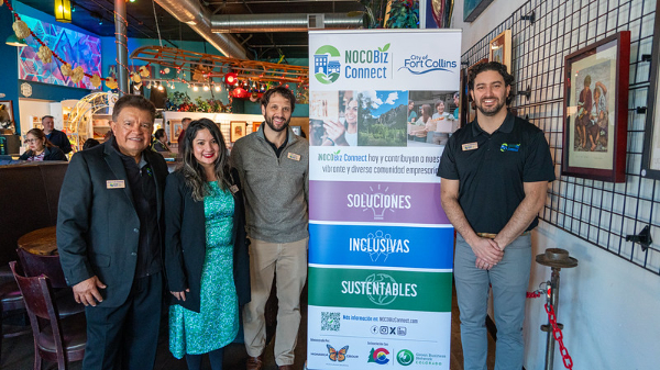 Four people standing next to a sign