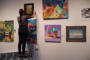 Artist hanging artwork at an Open Hang event.