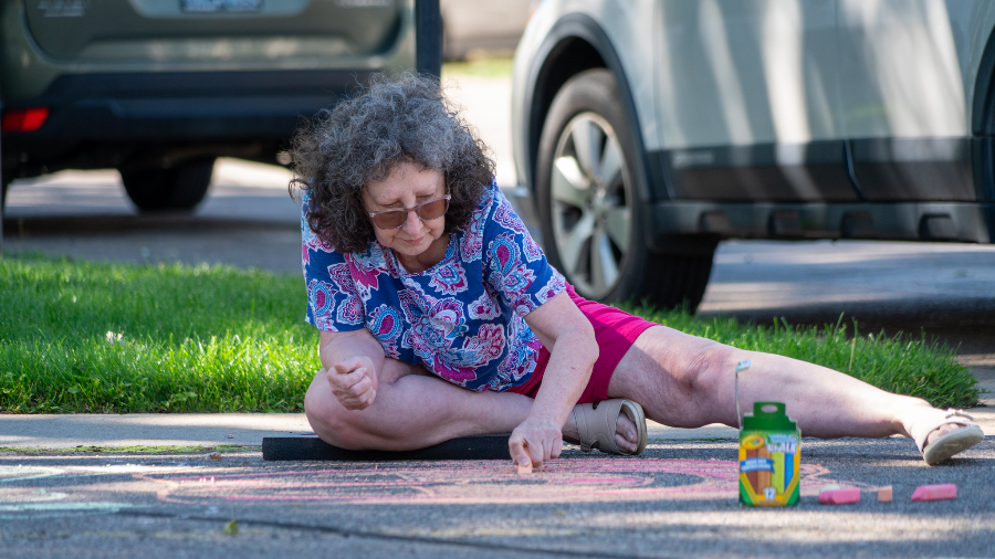 A community member creates chalk art at Skyview Mobile Home Park during Chalk the Block chalk art pop-up series in Aug. 2024.