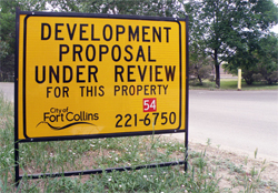 A yellow development review sign along the road