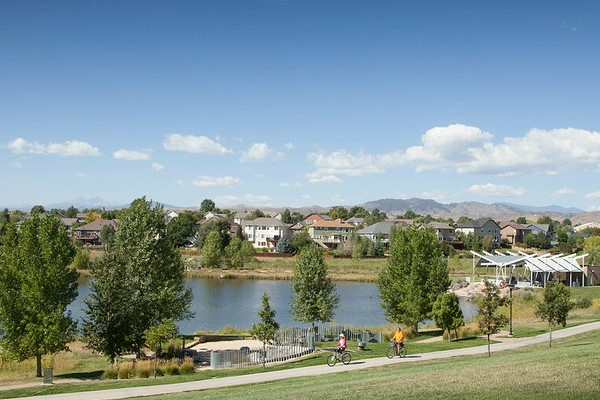 A photo showing a park, bike path, picnic areas, homes, and a small lake