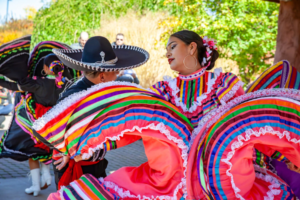 Mariachi band plans alongside Hispanic dancer.