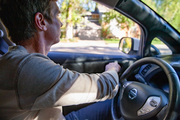 Driver using the opposite hand to open car door.