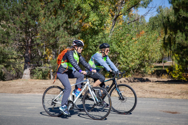 Two people biking together side by side, smiling