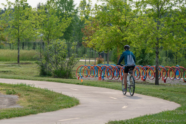 A person biking on bike trail passing colorful bike racks