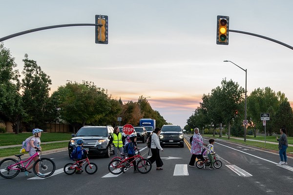 Children walking their bikes in the crosswalk.
