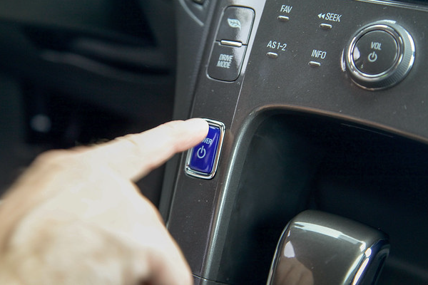 Person pushing the start button on an electric vehicle