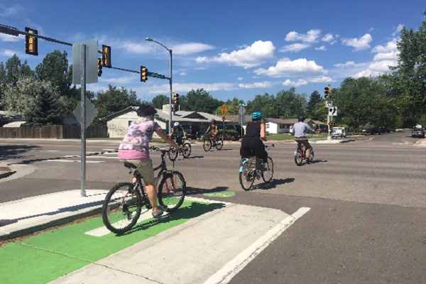 Bicyclists riding through a Toucan intersection in the summer.