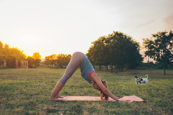 woman in a downward dog position with a puppy in the background