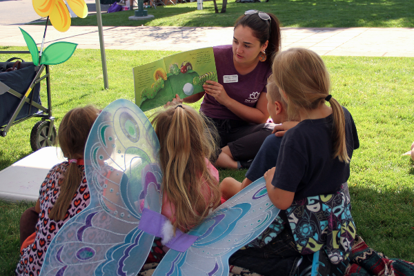 staff reading a book to children during read and seed
