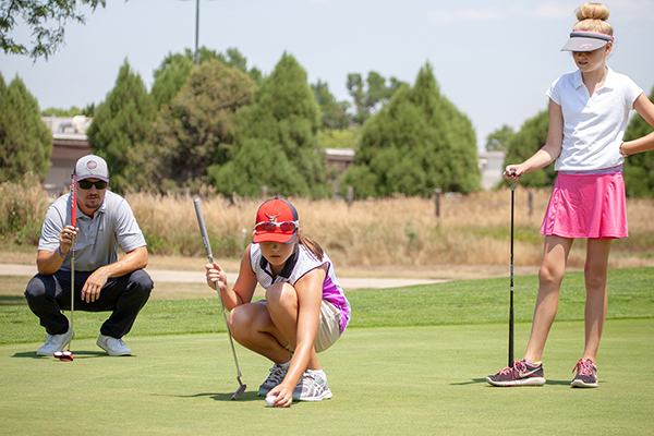 girls on putting green lining up a putt