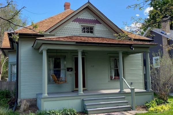 A single story blue home with front facing gable clad in fishscale shingles