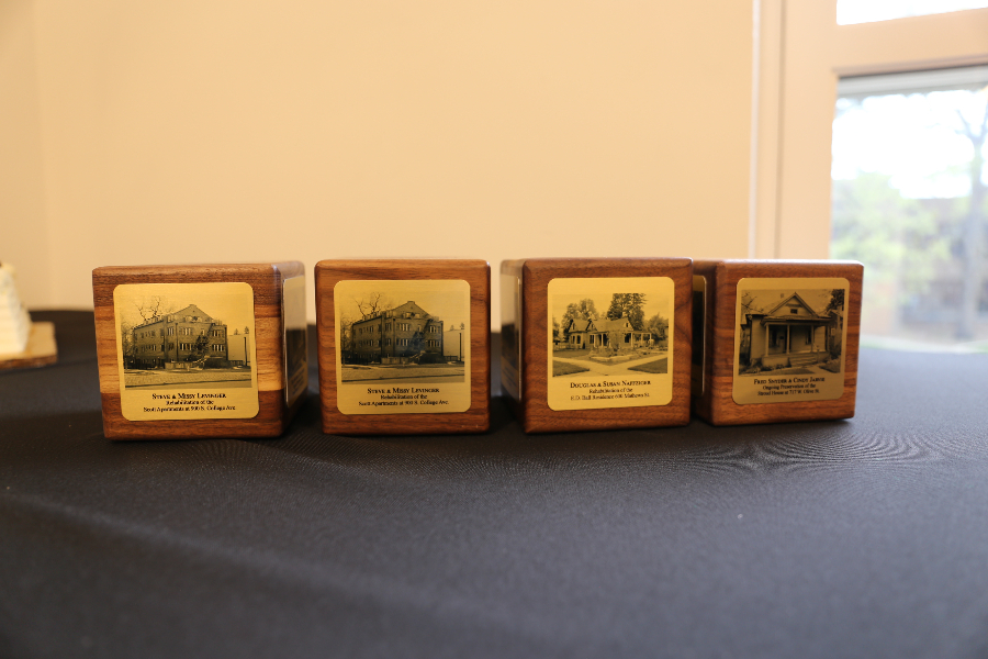 Four square wood blocks with bronze plaques attached on a black tablecloth