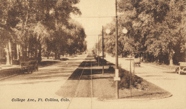 A sepia-toned historic photo depicting a tree-lined two lane street with a median and trolley tracks