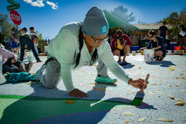 city employee painting a street mural