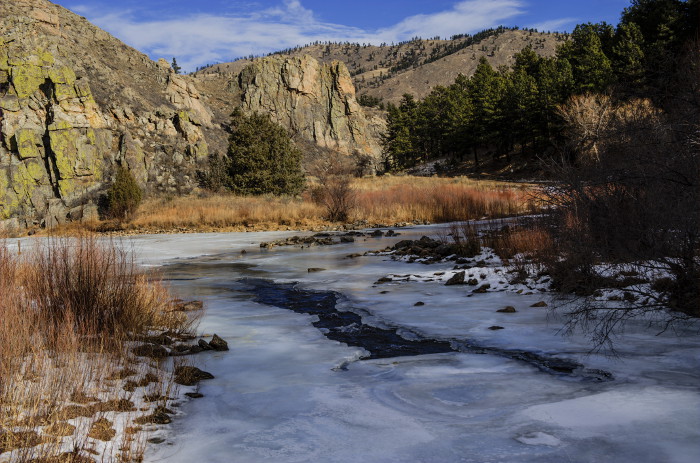 A frozen over river surrounded by trees. Linked to Gateway natural area pass.