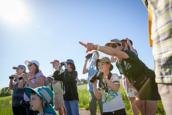 kids and adults looking into the distance with a volunteer pointing
