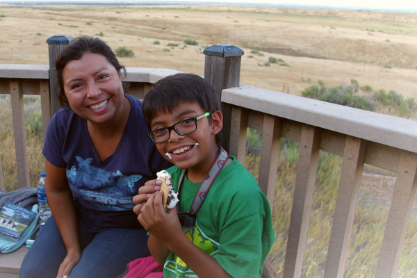 kid and parent smiling while eating smores