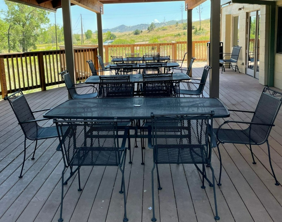 three metal tables in a line with chairs surrounding them and mountains in the distance