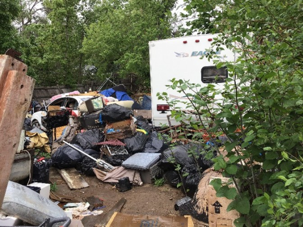 Very messy yard with scattered junk and RV
