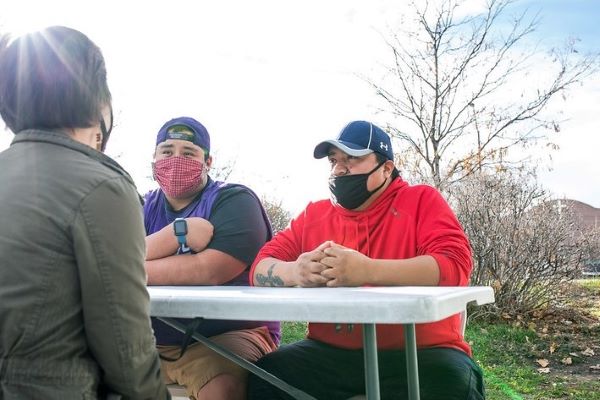 People in masks, talking at a table