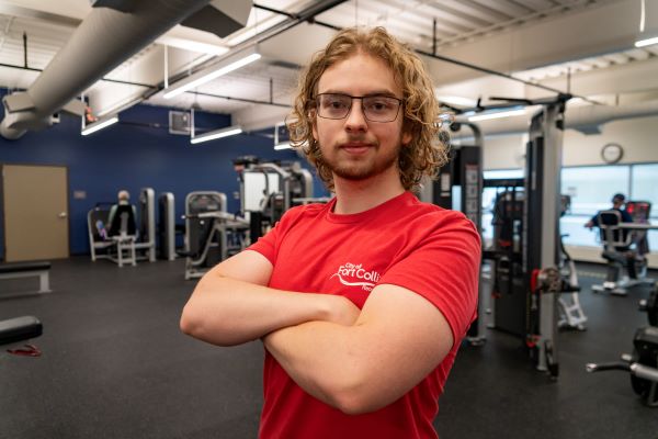 Skye Dyer posing with crossed arms in a weight room