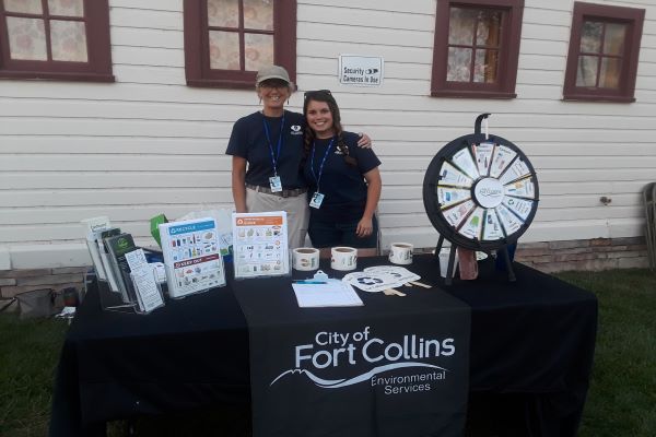 Two people posing behind an event table.