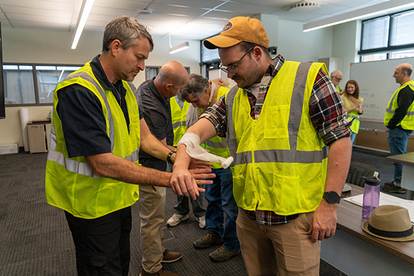 A photo of two people practicing use of a bandage.