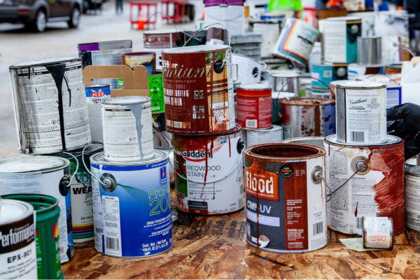 Used paint cans sit in a pile, dried paint drips on the sides.