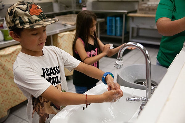 Kids washing hands in commercial kitchen sink