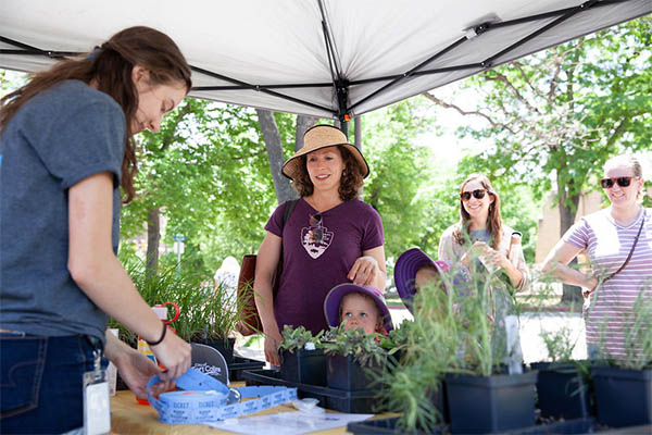 Community members collect free plants from a garden party staff member.