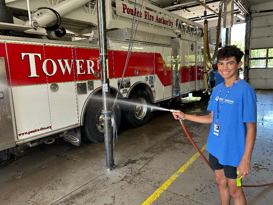 Teen smiling while washing a fire truck.