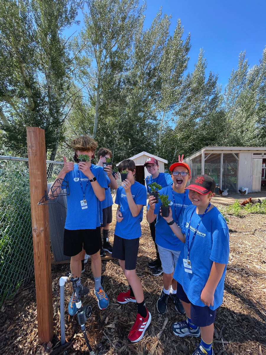 Group of teens holding plants and looking excited.